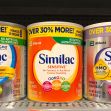 Three cans of Similac infant formula on a grocery store shelf.