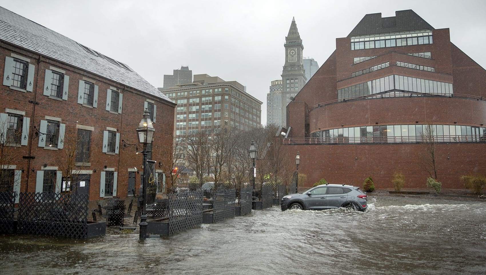 Flooding seawater splashes against a car on Long Wharf in 2018. (Robin Lubbock/WBUR, File)