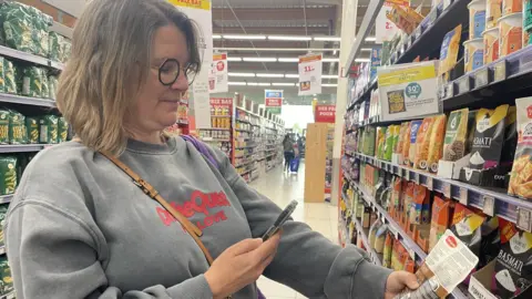 John Laurenson Nathalie uses her phone to scan a product.