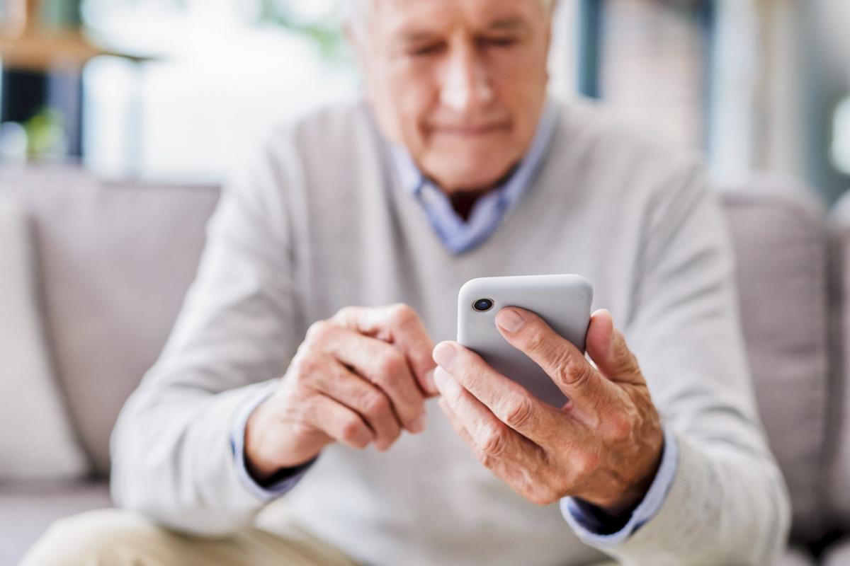 Senior man using a phone at a clinic