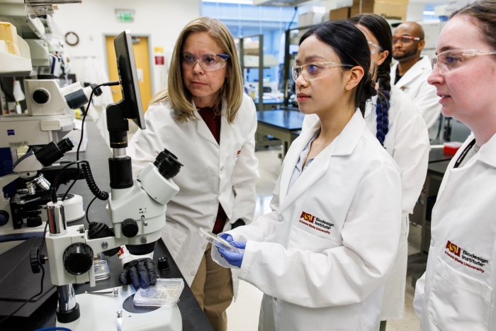 Haydel and a group of students examine TB samples with a microscope in the lab.