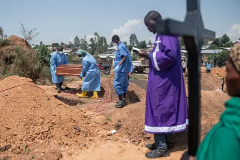 Getty Images A priest conducts a blessing ceremony at Mbiyo cemetery for a fourth orphan who died from Ebola virus disease at an orphanage in Bunia, Ituri Province, June 19, 2026