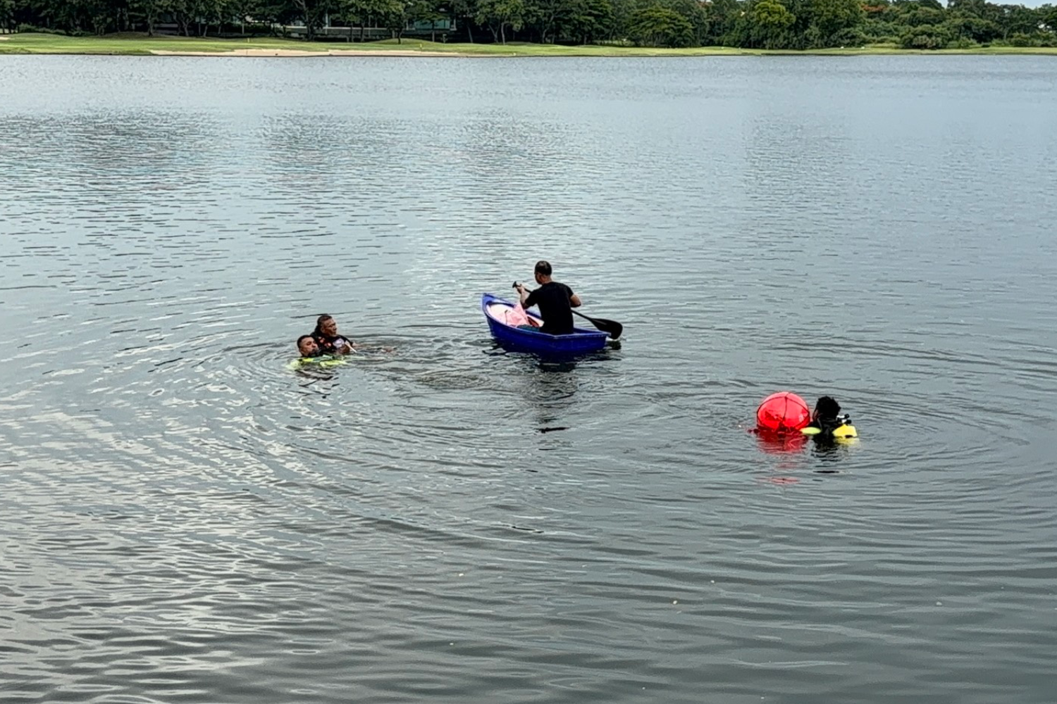 Rescue divers work to retrieve the body of the American national who jumped into the lake inside a housing estate before drowning in Samut Prakan on Tuesday evening.