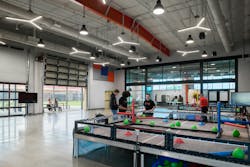 Interior robotics arena with configurable test and activity stations, and garage doors to exterior