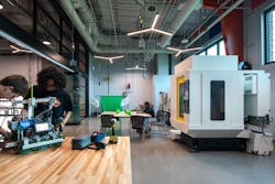 A makerspace in the STEM center features glass and metal partitions, open industrial ceilings, fabrication tools, and other equipment