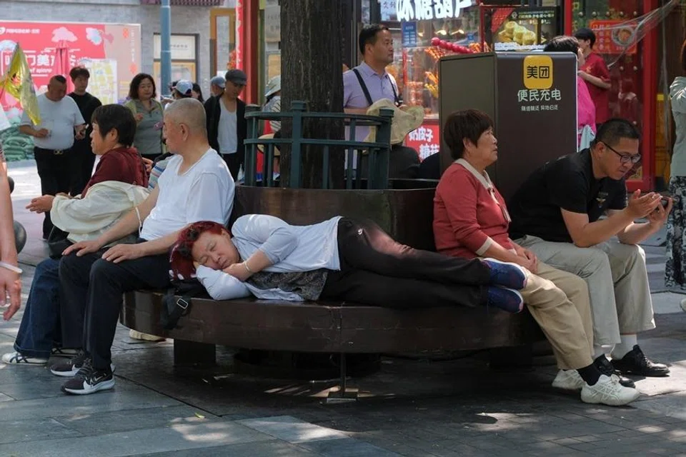 People rest on a bench along Qianmen pedestrian street, in Beijing, China, on 13 May 2026.