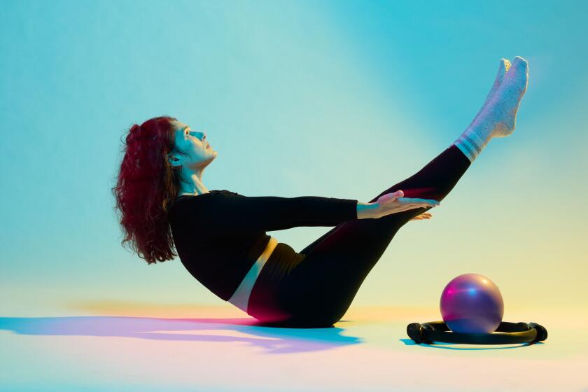 Photo of a woman stretching with pilates equipment, in colorful lighting.