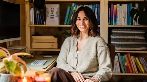 Vicki Knights Sula in her office surrounded by books, candles and a plant