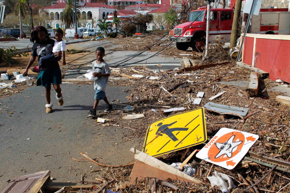 A woman and her children walk past debris left by Hurricane Irma in Charlotte Amalie, St. Thomas, U.S. Virgin Islands, on Sept. 10, 2017. (AP Photo/Ricardo Arduengo, File)