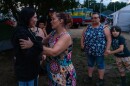 A community member talks to Kahla Wilson, left, as her sister Kristi Contreras stands by at the 63rd Annual Mii-gwitch Mahnomen Days Powwow on July 18, 2026, at the Ball Club Community Center in Ball Club. Wilson and Contreras are sisters of Rikki Skog, who died two days earlier under suspicious circumstances.