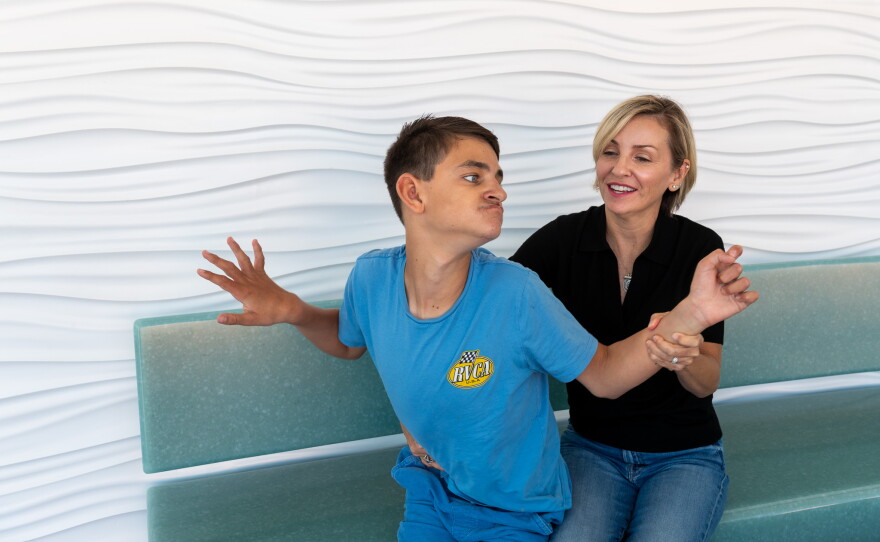 Connor Dalby, 17, sits with his mom, Kelly Del Real, at Rady Children's Hospital on July 22, 2026. Del Real says the personalized treatment for her son's rare genetic condition has given him the chance to experience some of the firsts of being a teenager.