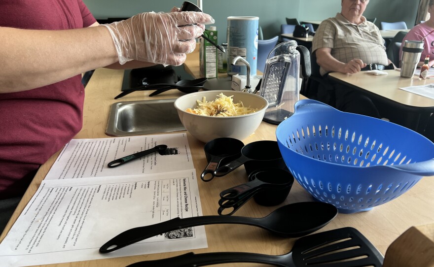 Natasha Ridenour reads over a mac n cheese recipe as class members look on