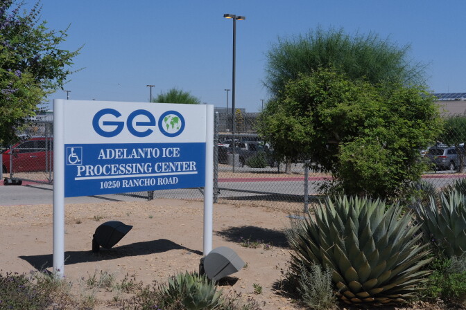 A sign for the private prison company GEO Group stands outside the gates of an immigrant detention facility in Adelanto, California.