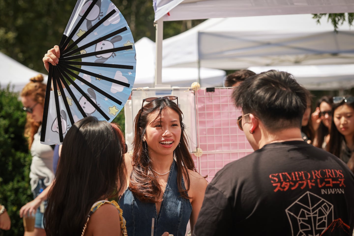 Savannah Ung working with Connie OMG used a fan to cool off customers, Dy Uong and Brian Dinh, at the MAUM Market, a pop-up spotlighting Asian-owned small businesses at the Seaport.