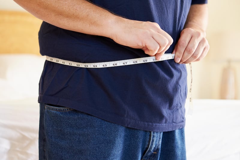 Close up of overweight man measuring waist