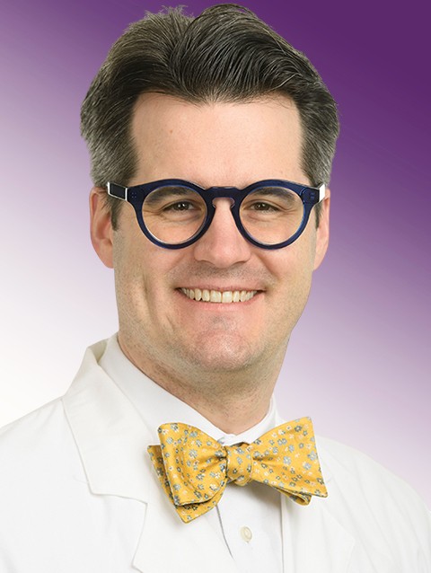 Dr. Ryan Hofler wears a white coat and smiles.