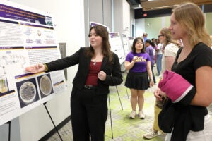 A female researcher explains her work and engages with a male attendee.