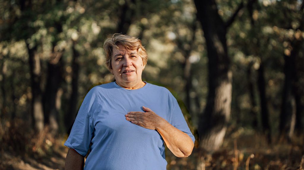 older white woman placing a hand over her heart in discomfort