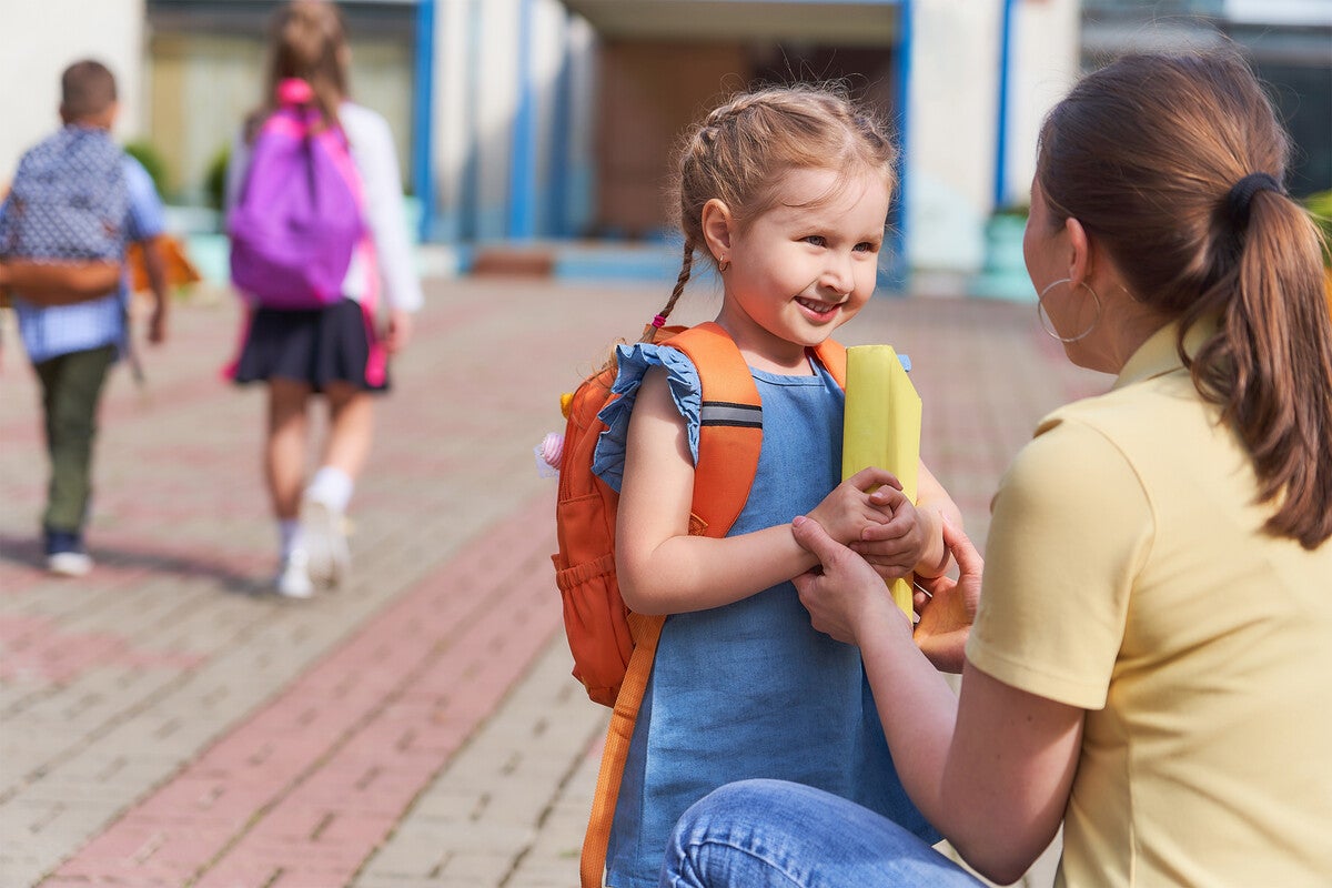 Young girl with backpack looks at her mother.