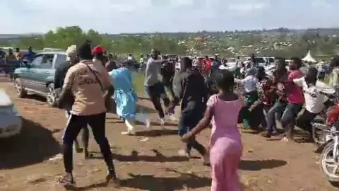 X Daniel Uyirwoth Welo is seen wearing blue scrubs running through a crowd of people as they start to chase him at a cemetery in Bunia