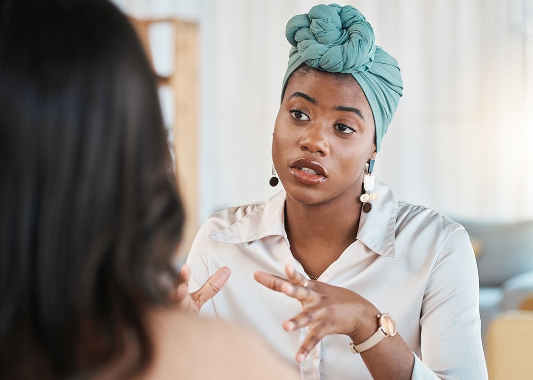 A young black female entrepreneur in discussion with a colleague. - PeopleImages // Shutterstock