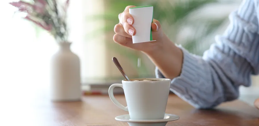 Close up of a woman hand throwing saccharin pill on coffee cup at home