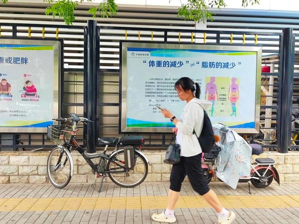 A woman walks past a display promoting weight management in China.