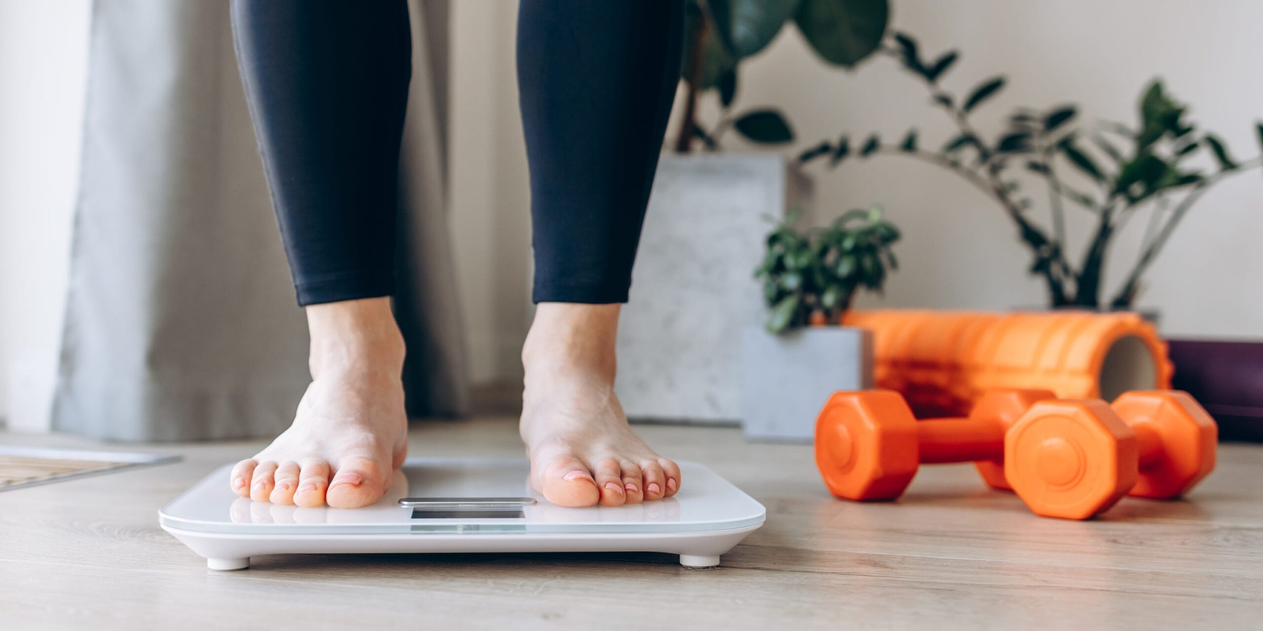 A close-up view of a young woman standing on a weighing scale. Dieting, healthy lifestyle and achieving weight goals concept