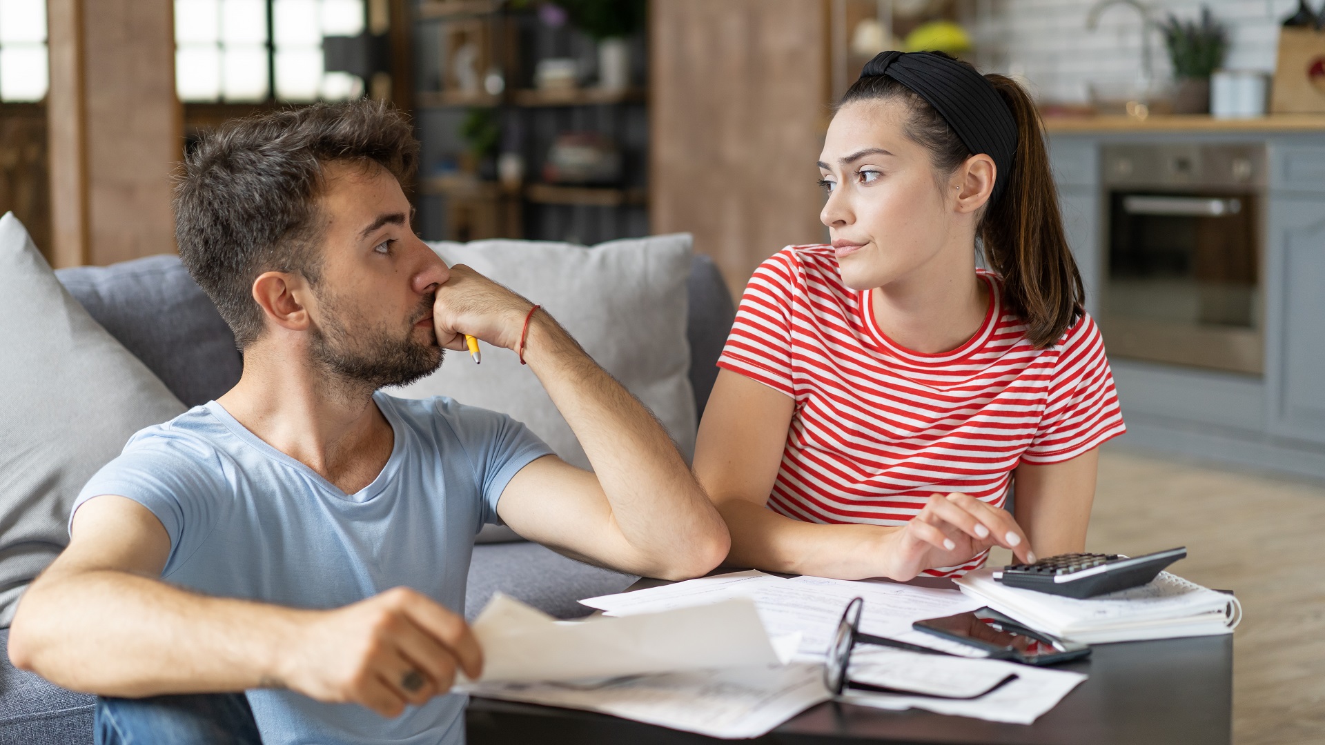 Discover a frustrated broke couple sitting in living trying to fix budget, spending and money habits