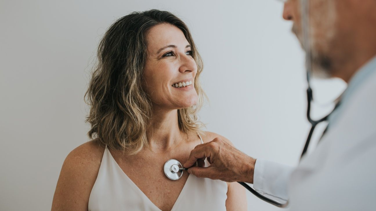 Middle-aged female having her heart listened to by a healthcare professional