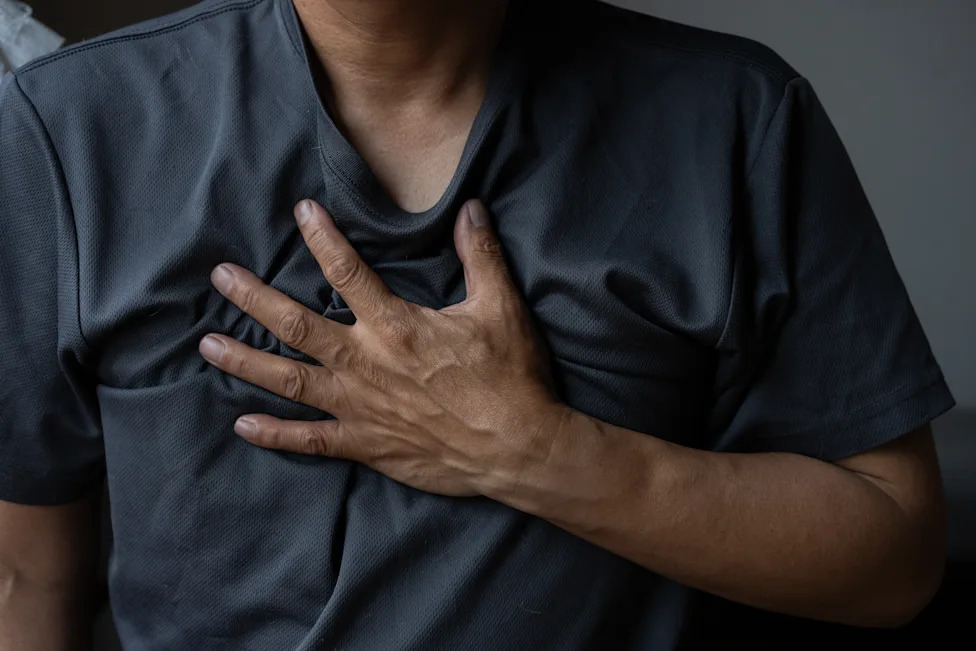 Upper body of a man clutching his chest