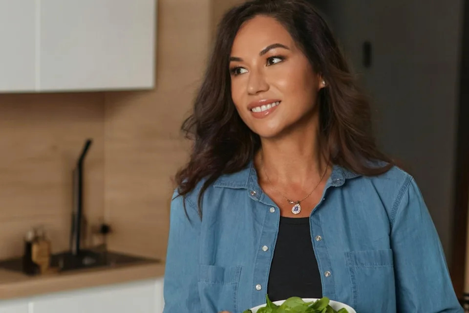 Faye James in a kitchen holding a bowl of spinach