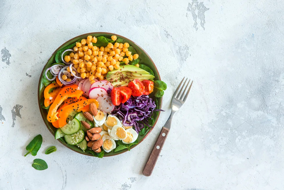 A colorful bowl filled with vegetables, chickpeas, eggs, and avocado shows how volume eating focuses on nutrient-dense, high-volume foods that can help you feel full while keeping calories lower.