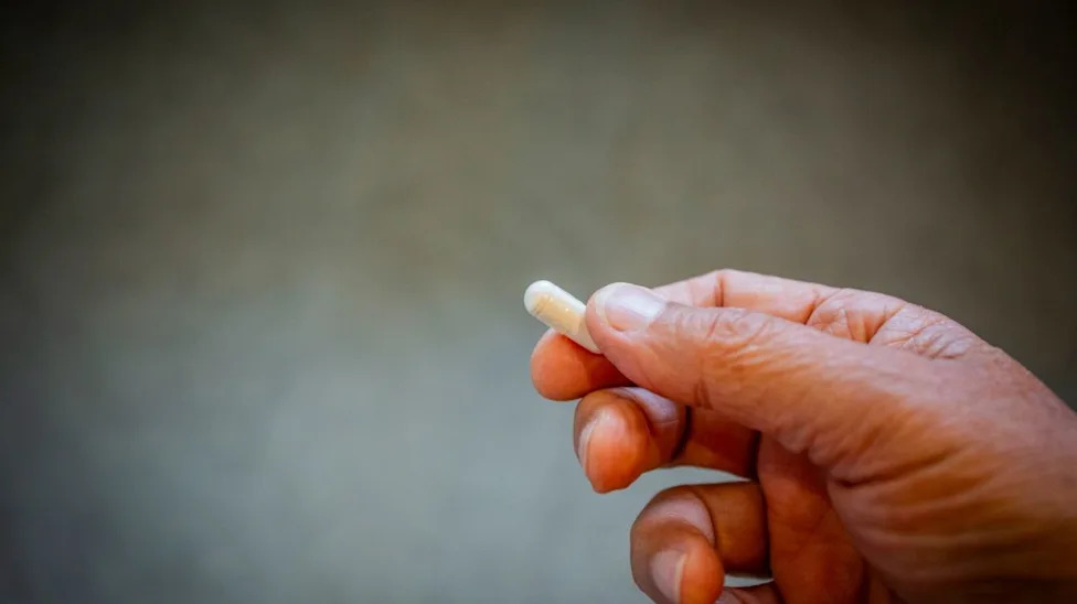 Closeup of a person's hand holding a pill.