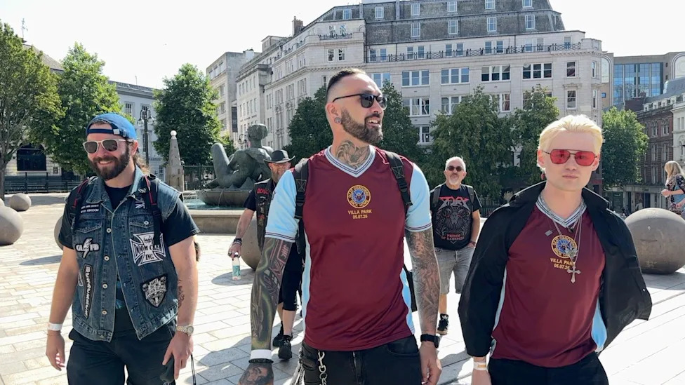 Three men wearing sunglasses, two wearing Aston Villa tops and a third wearing a denim jacket, gather in Victoria Square, Birmingham.