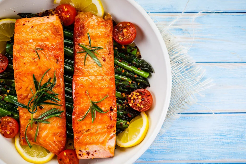 grilled salmon with asparagus and vegetables in pan on wooden table