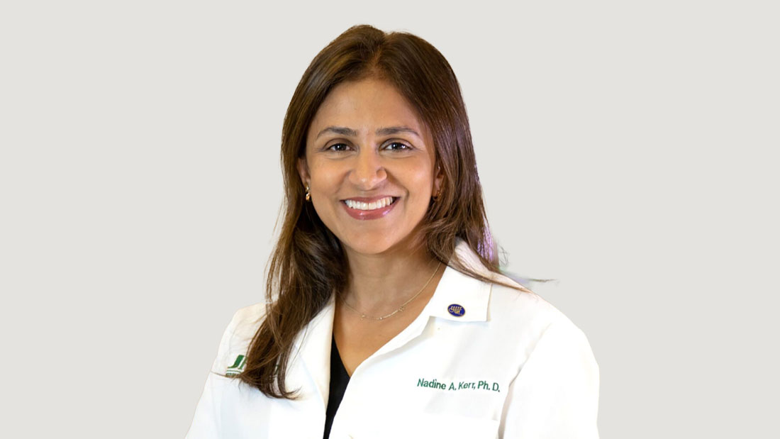 Dr. Nadine Kerr, smiling in her white medical coat