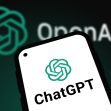 Smartphone displaying the ChatGPT icon with the OpenAI logo in the background