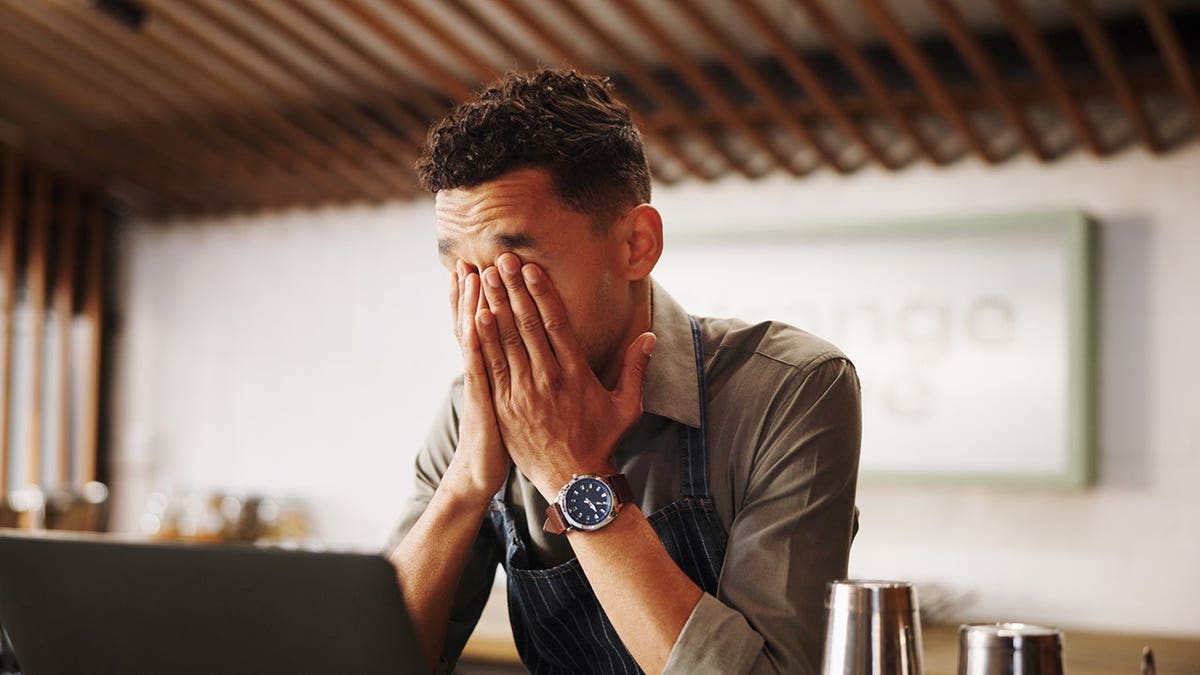 Man sits at a laptop in a bar.