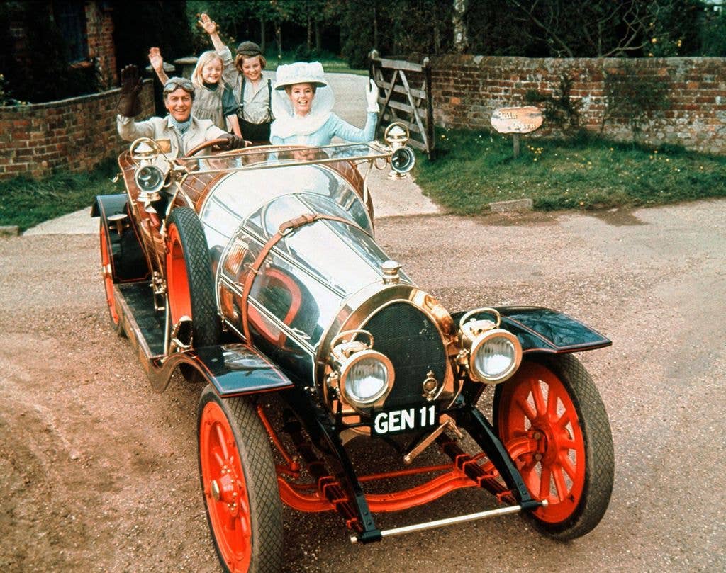 Dick Van Dyke and Sally Ann Howes wave from a vintage car with children.