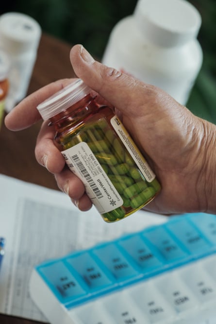 A hand holding a bottle of green pills.