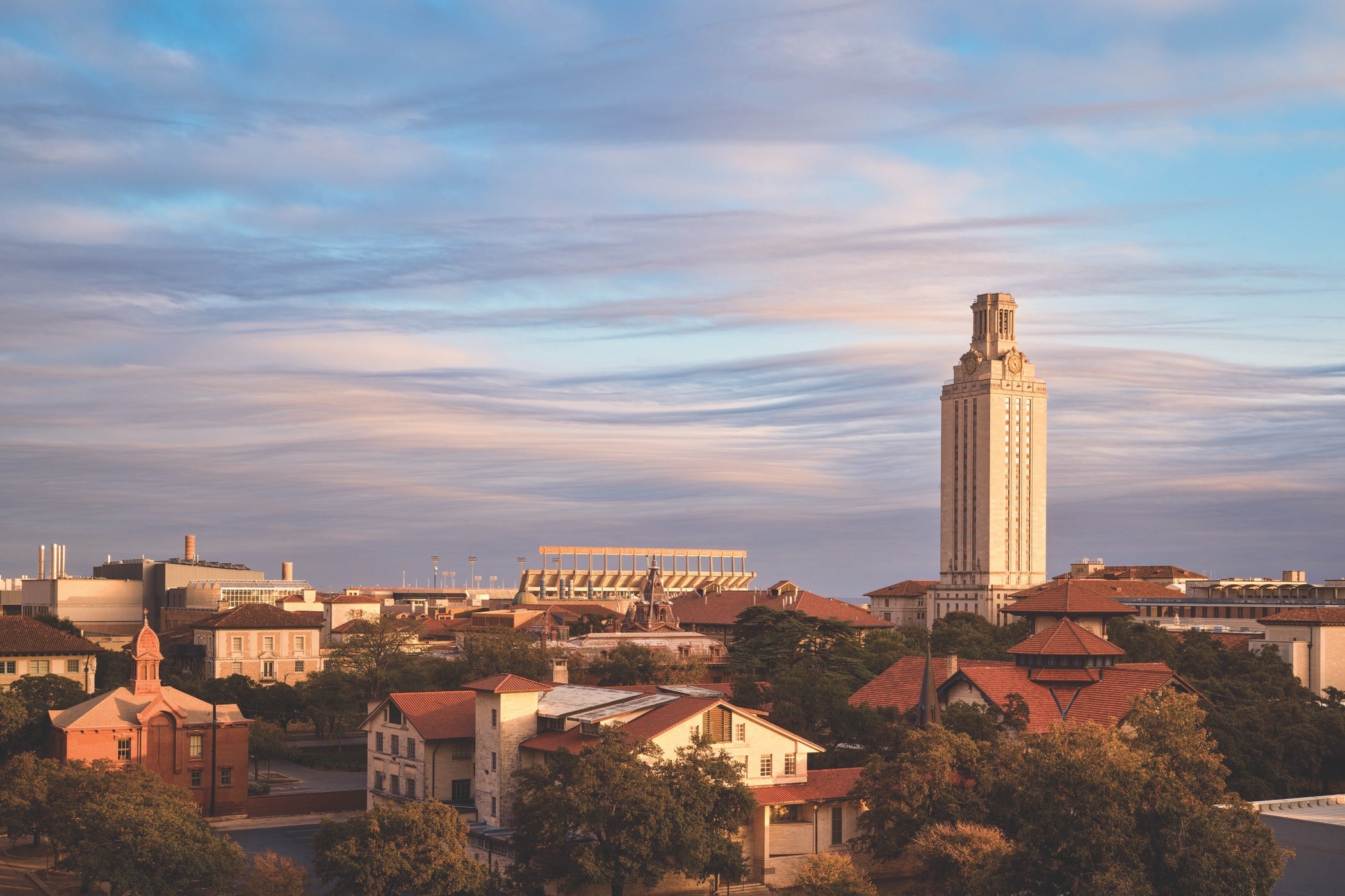 The University of Texas at Austin campus early at sunset with the Tower beneath a partially cloudy sky