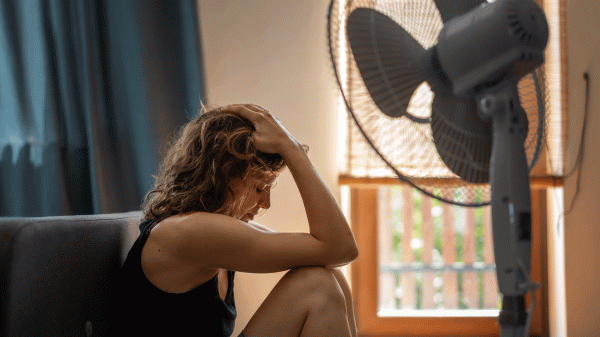 woman sitting in front of a fan with her head in her hands