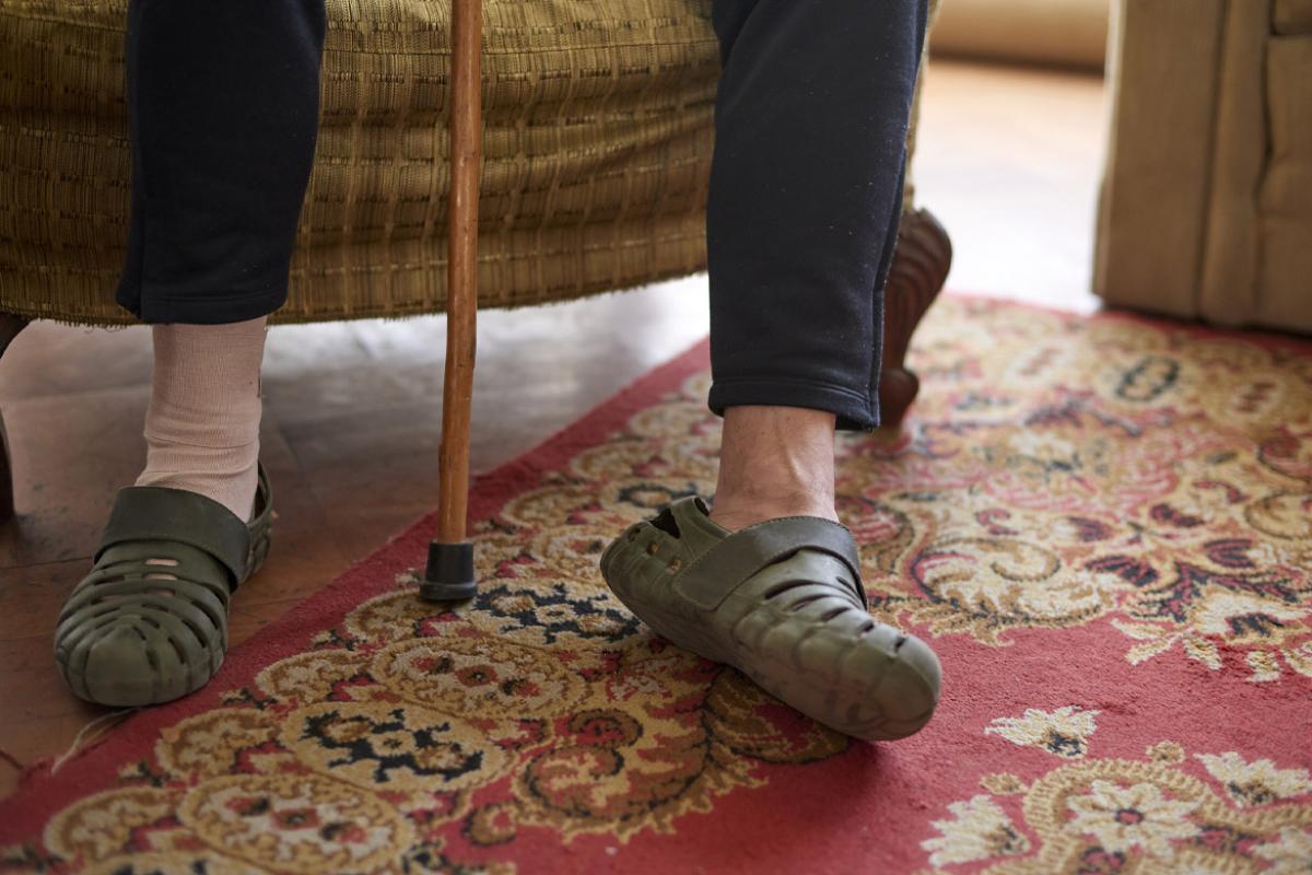 Two feet, one of them injured and bandaged, with a walking cane