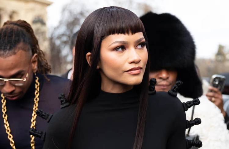 Zendaya in black, with long straight hair and blunt bangs.