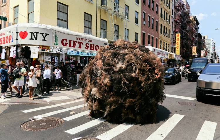 K18's giant "Tumblehair" installation, a car-sized ball of tangled hair, rolling through a Chinatown street crossing in New York City as pedestrians look on and take photos
