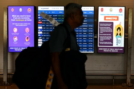 The silhouette of a passenger walking past screens