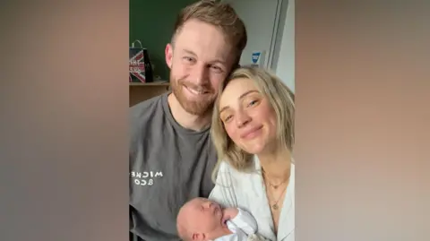 Family handout Becki and James are taking a selfie while holding their newborn baby boy Beauden.