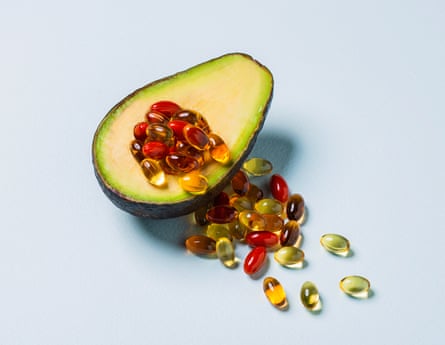 An avocado with shiny pills spilling out from its centre