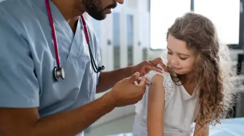 Getty Images A doctor vaccinating a young girl.